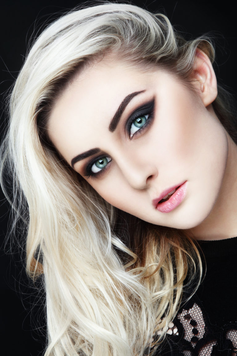 Portrait of young beautiful woman with long platinum blond hair and stylish winged eyes make-up